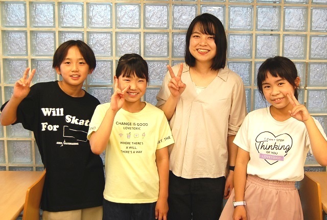 笑顔でピースする小学生と講師