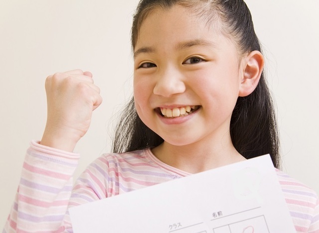 いい点数をとって喜ぶ小学生の女の子と、個別指導の授業